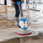 Asian worker cleaning sand wash exterior walkway using polishing machine and chemical or acid